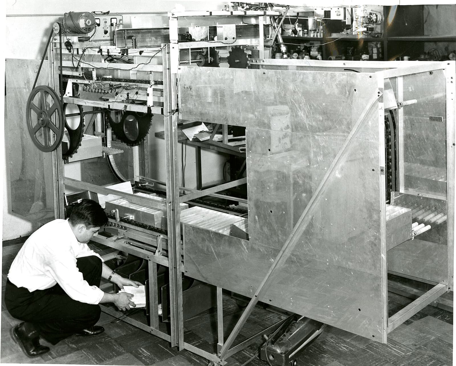 A prototype high-speed letter-sorting machine built for the Post Office, an engineer working at its base